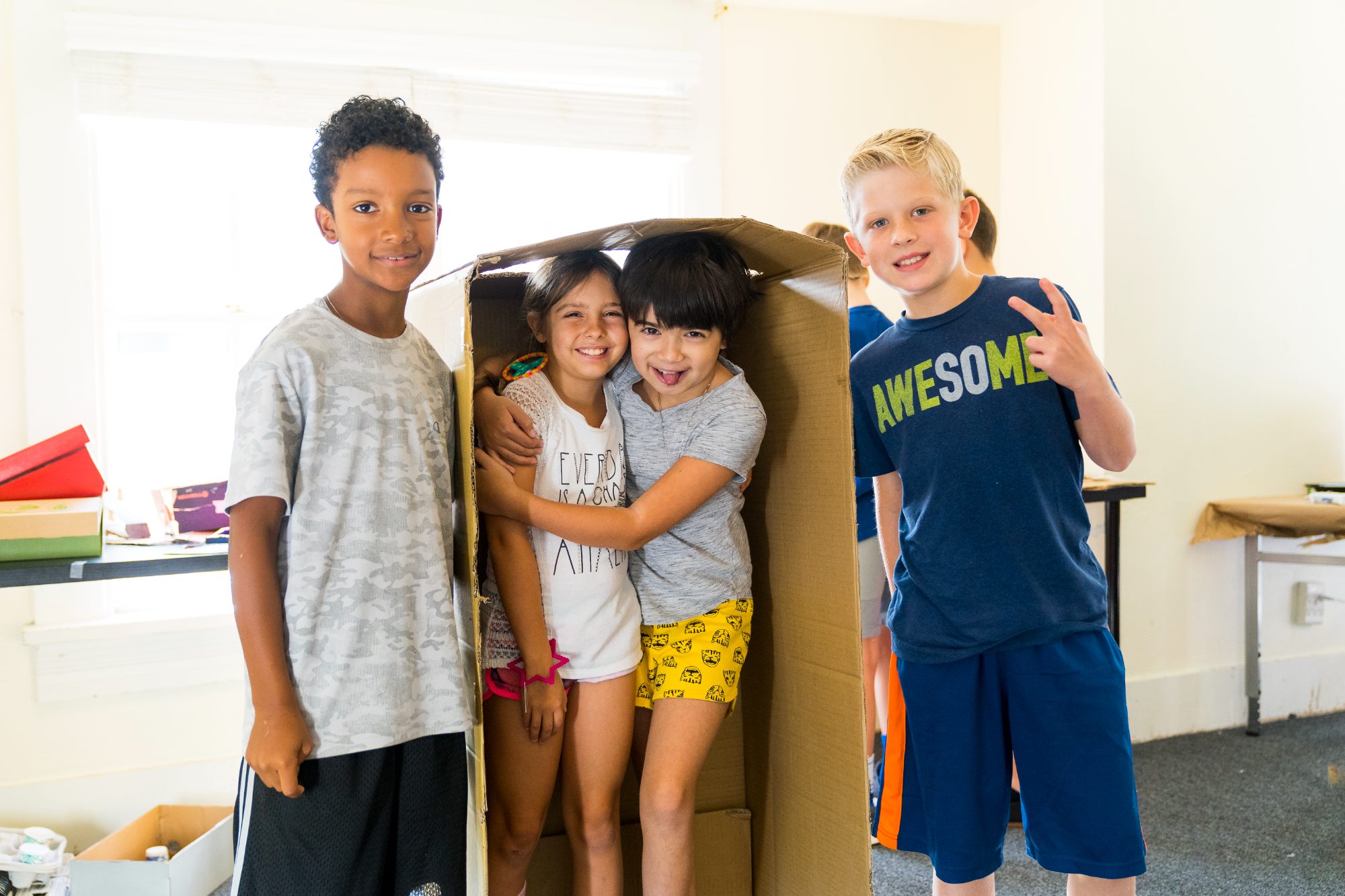 Four smiling Campers showing off the cardboard fort they built